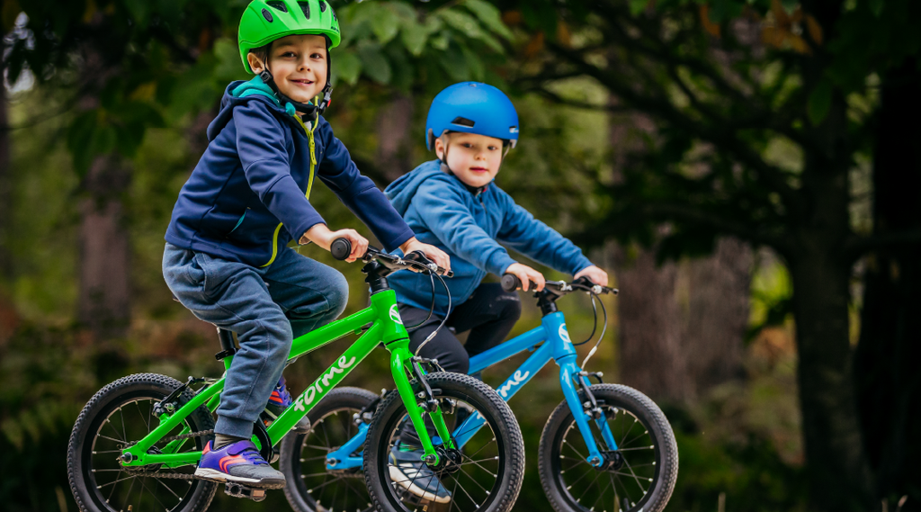 Zwei Jungs fahren auf ihrem grünen und blauen Forme Cubley Kinderfahrrad durch den Wald