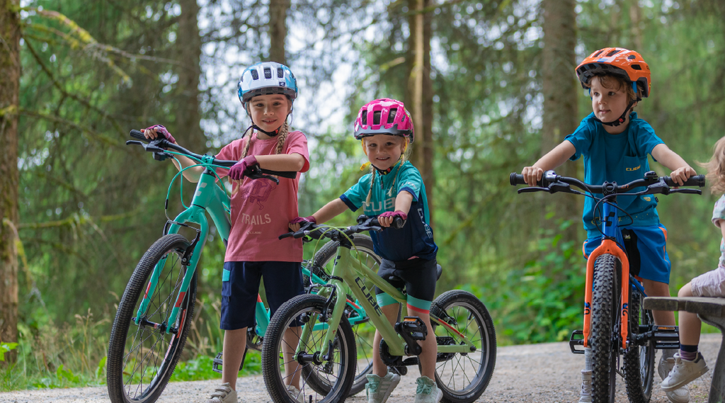 Kinder stehen mit ihren Cube Kinderfahrrädern im Wald
