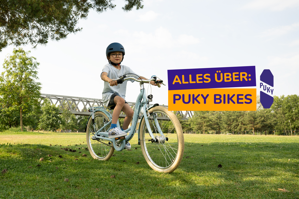 Junge mit Fahrradhelm fährt auf blauem Puky Skyride Kinderfahrrad durch den Park