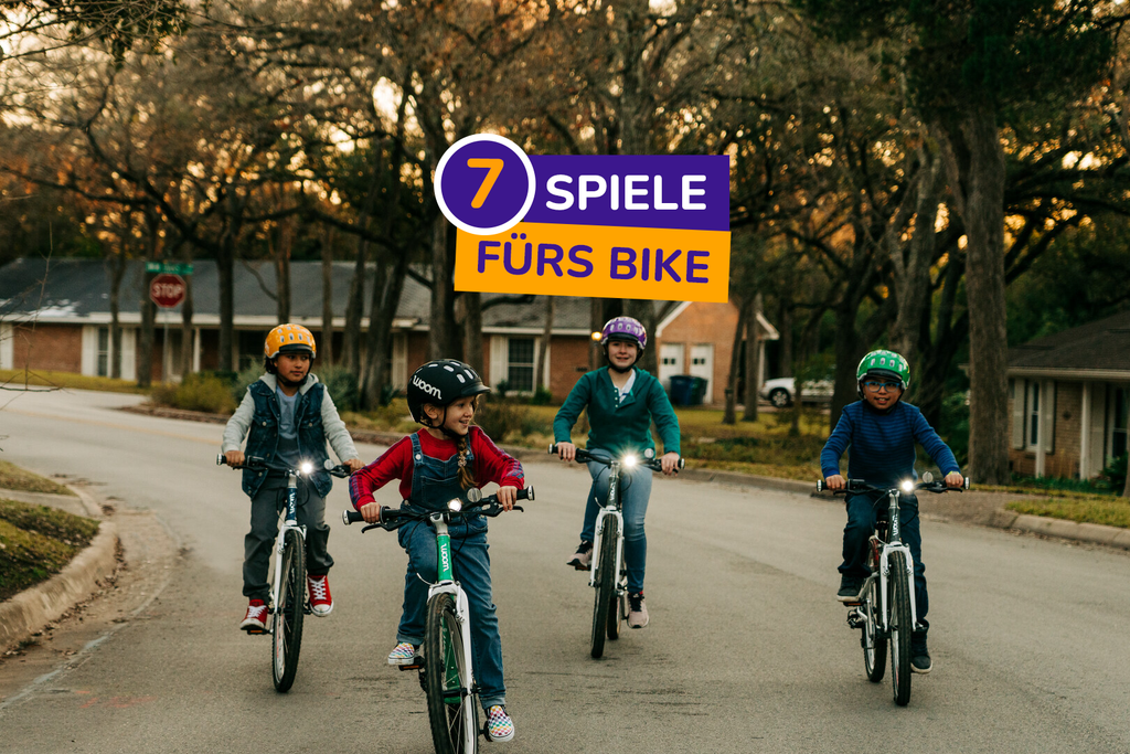 Vier Kinder fahren mit ihren Woom Kinderfahrrädern eine Straße lang