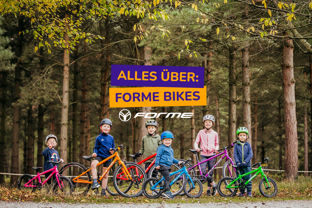 Eine Gruppe Kinder stehen mit bunten FORME Kinderfahrrädern im Wald