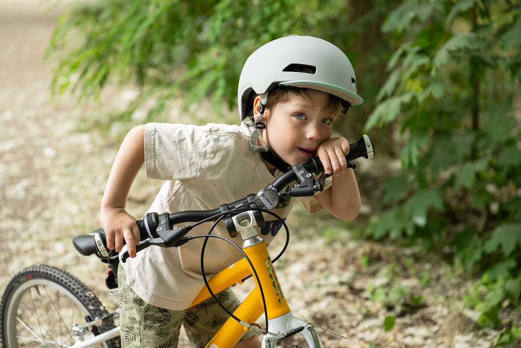 Junge mit Fahrradhelm lehnt sich auf seinen Fahrradlenker