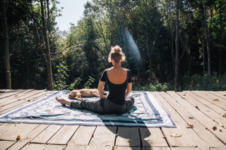 Lynn sitting in lotus - crossed legs - on the deck of her place with her dogs around her.