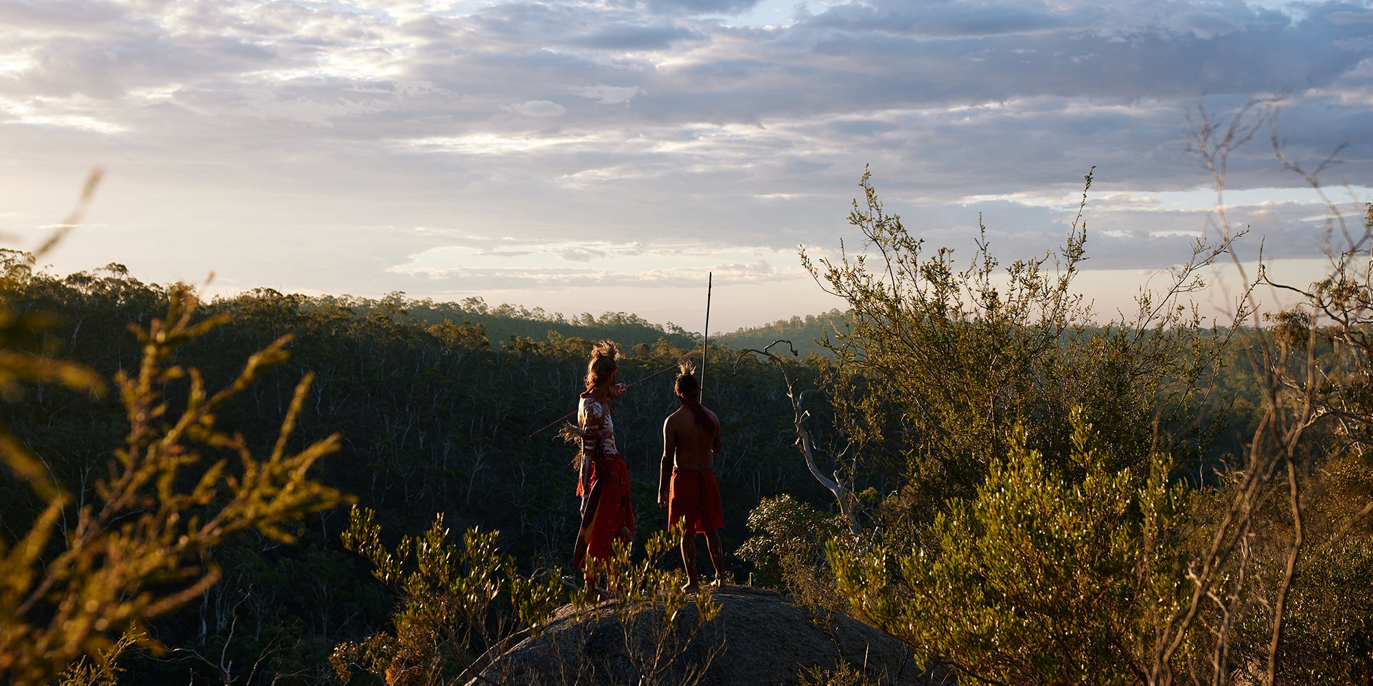 First Nations Men in traditional dress looking over land 