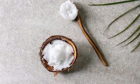 Coconut oil in a wooden cup and a spoon with coconut oil