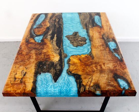 A rich dark live-edge dining table made with FlowCast®, and bright blue iridescent EcoPoxy Metallic Pigments.