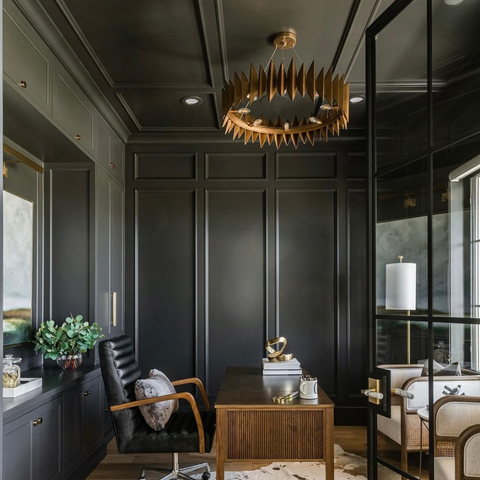 Black home office with large gold round chandelier hanging over the desk