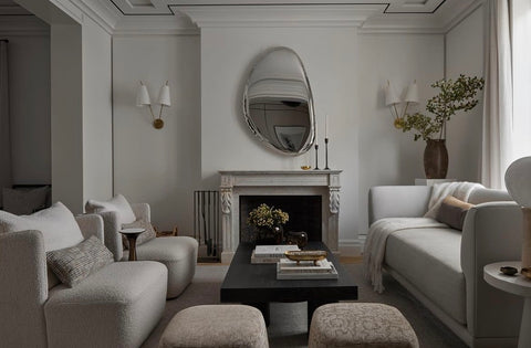 A white, cozy living room with hudson valley sconces and white furniture.