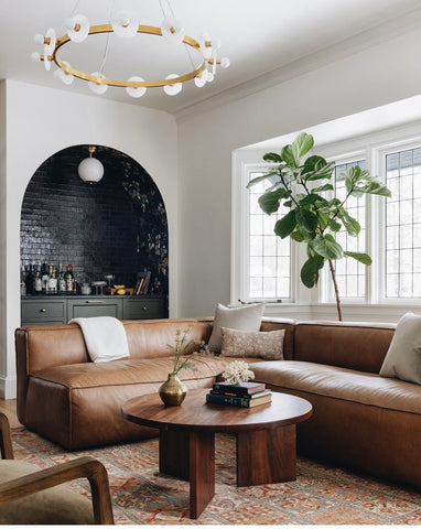 A leather sectional with a brass ring chandelier.