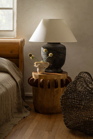 Pecola cement table lamp with gold etchings sitting on a bedside table