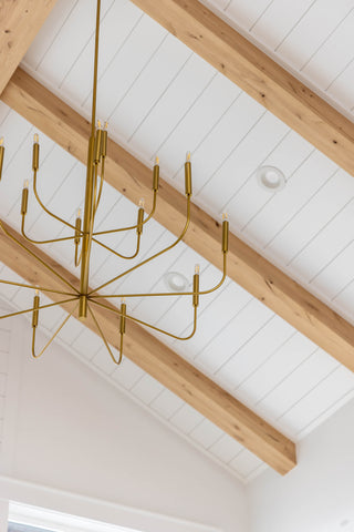 A two tiered brass chandelier on a lofted ceiling.