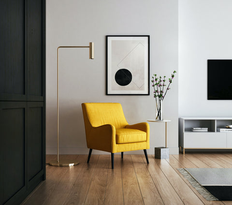 A yellow chair in a living room with white walls and wooden floor.
