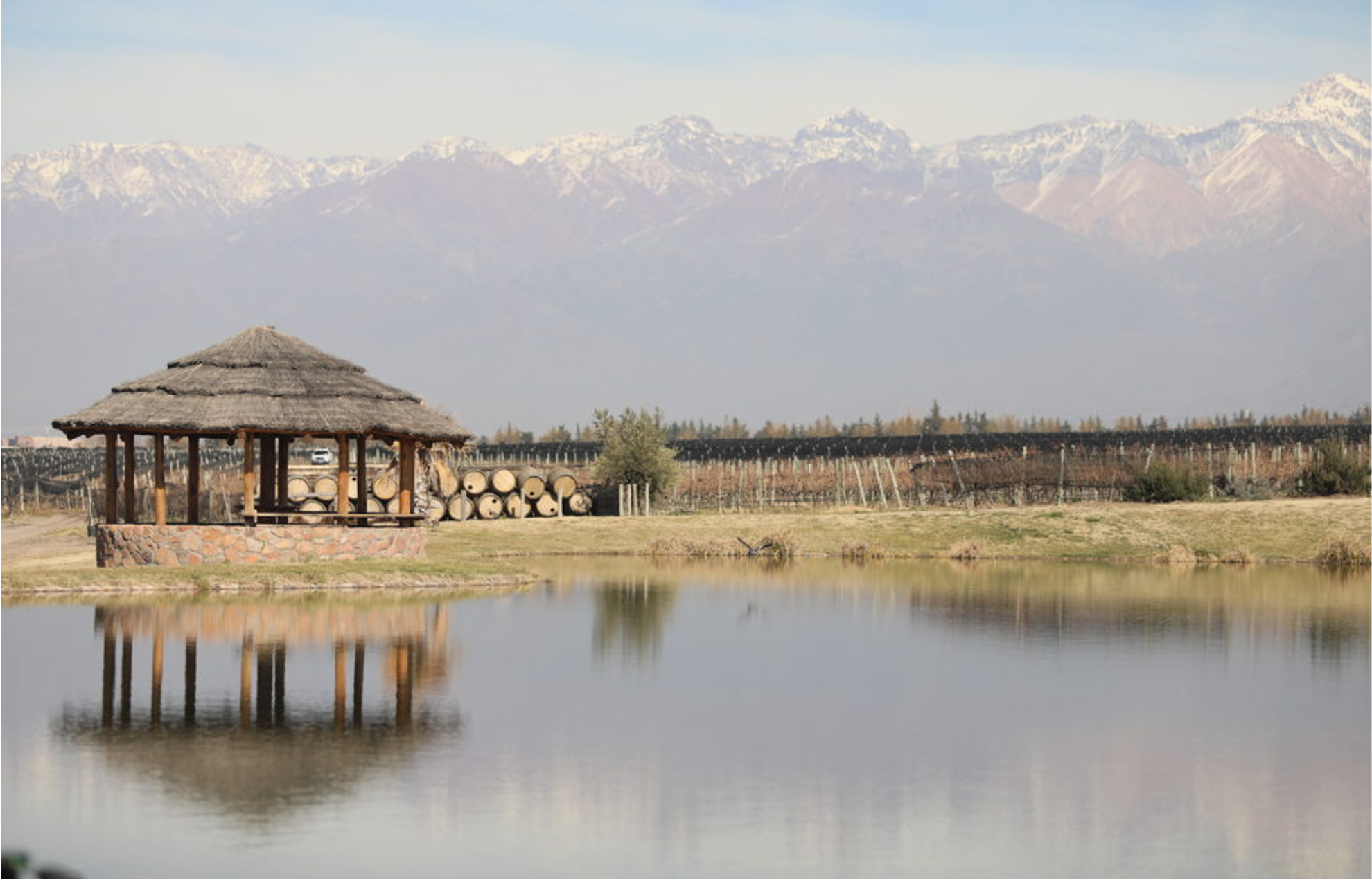 A straw hut in a pond with a scenic view of a large mountain range.