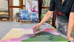 Blick auf den Maltisch einer Künstlerin die ein buntes Bild mit dem Spachtel malt