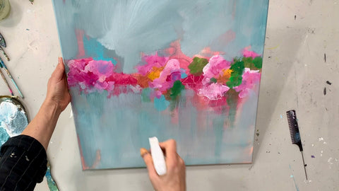 Blumenband in Rosa auf leinwand gemalt, türkise Farbfläche dazu und eine hand sprüht gerade Wasser auf das Kunstwerk