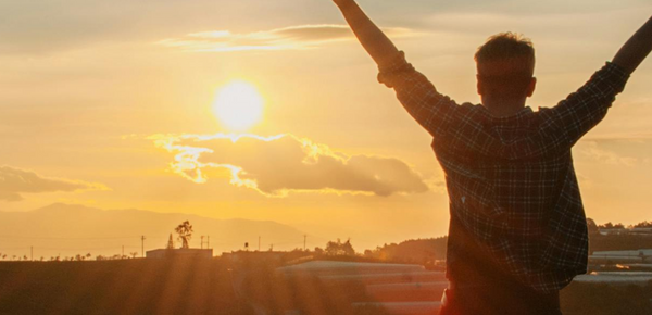 A Man Raising Both Hands to the morning sun