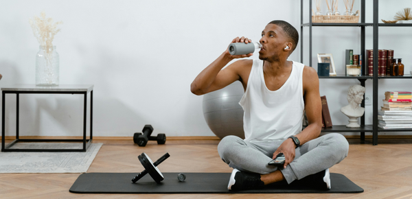 A man drinking a bottle of creatine and water after working out