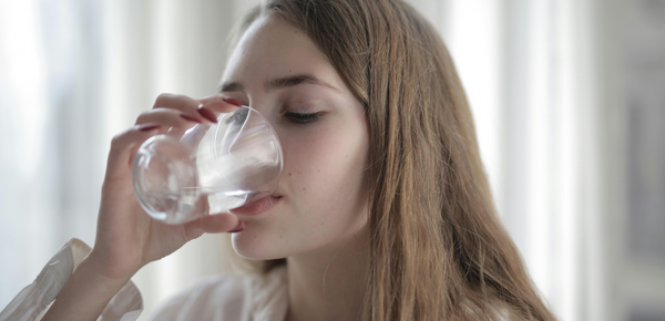 A teenage girl drinking a glass of water