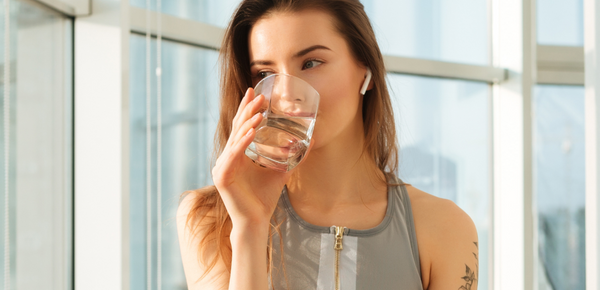 A woman drinking a glass of water after a workout
