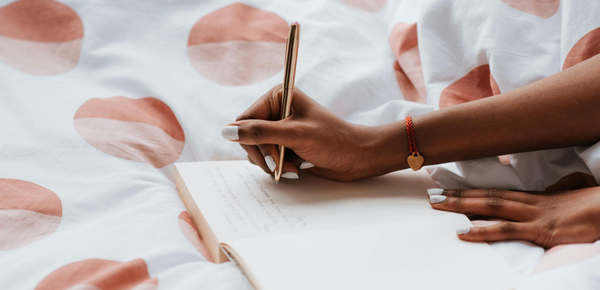 Close-up of Woman Writing in a Notebook in Bed