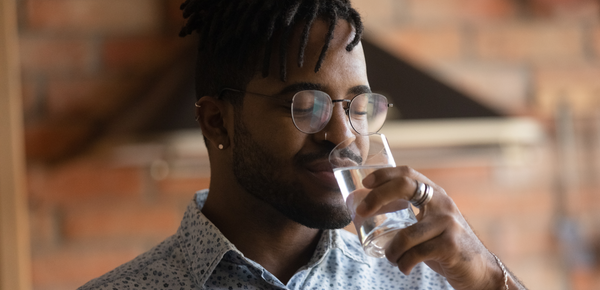 A man enjoying the taste and smell of a glass of fresh filtered water