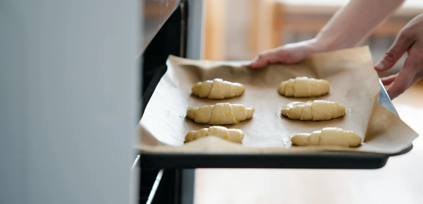 Freshly made croissants being put into an oven to bake