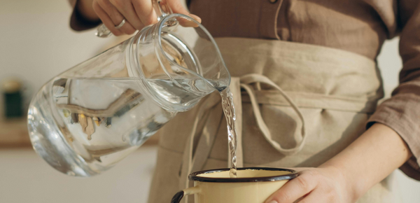 A baker pouring freshly filtered water into a cup