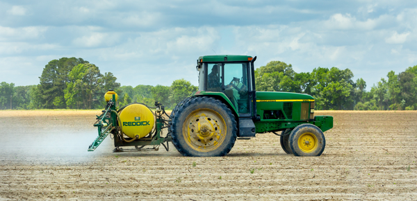 A tractor spraying fertilizer on a field