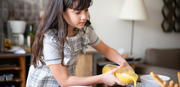 A girl pouring a glass of orange juice