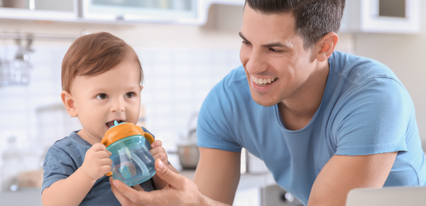 A father gives his baby a cup of fresh filtered water