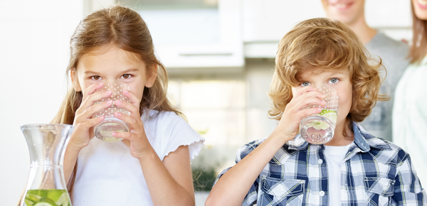 A young boy and girl enjoy glasses of fresh filtered water