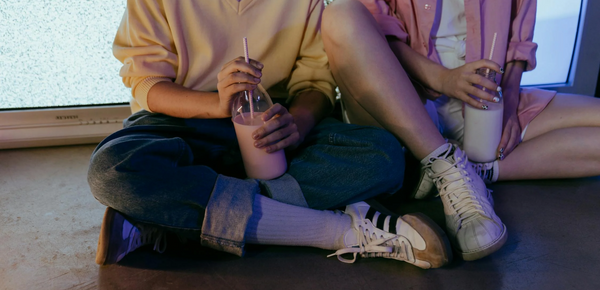 Teenagers holding milkshakes, sitting on the ground