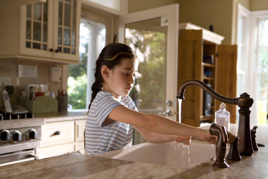 Girl running her hands under tap water in a kitchen