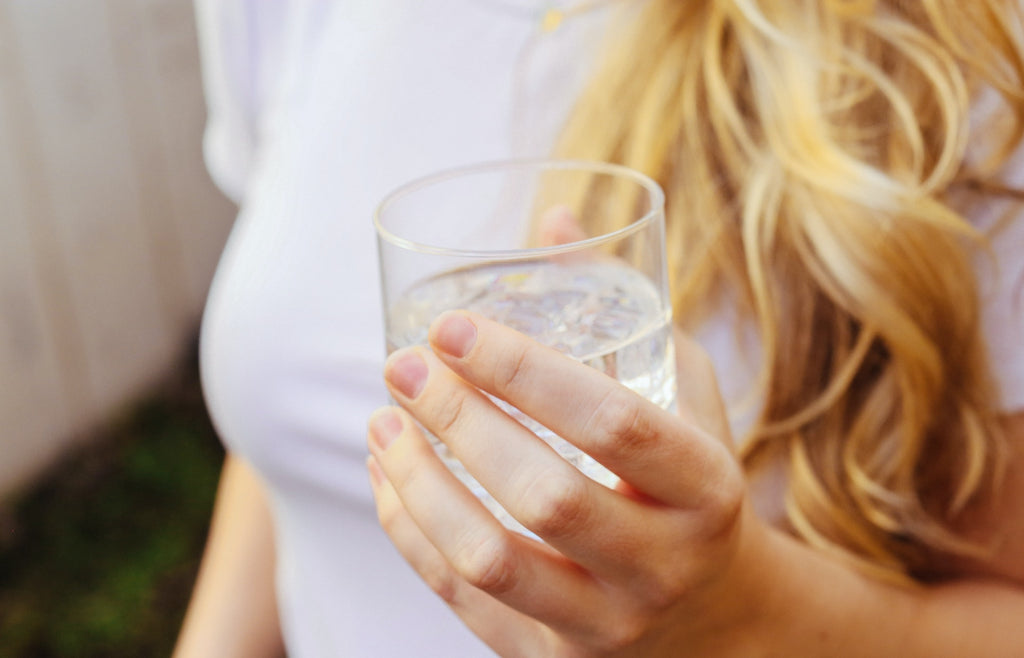 close up of a woman's hand holding a glass of water