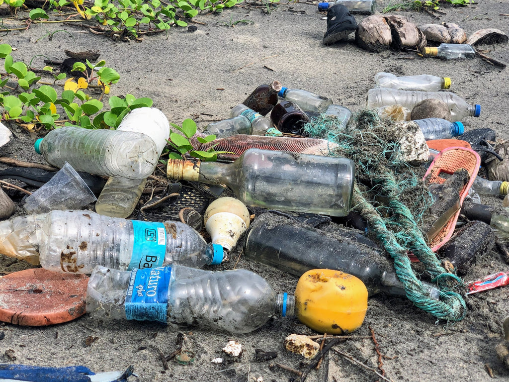 pile of waste on a beach including plastic water bottles