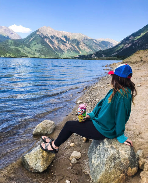 Women sitting by a lake with a water bottle in hand that has an Apollo Energy Gum sticker on it