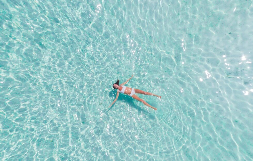 woman in bikini floating in ocean near the beach