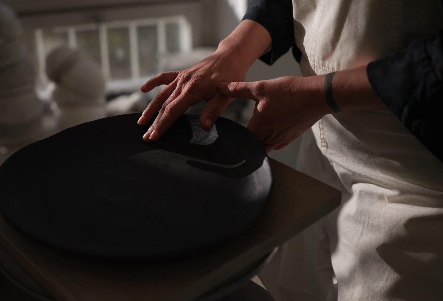 Close up of Hana Karim's hands shaping clay into artisan plates.