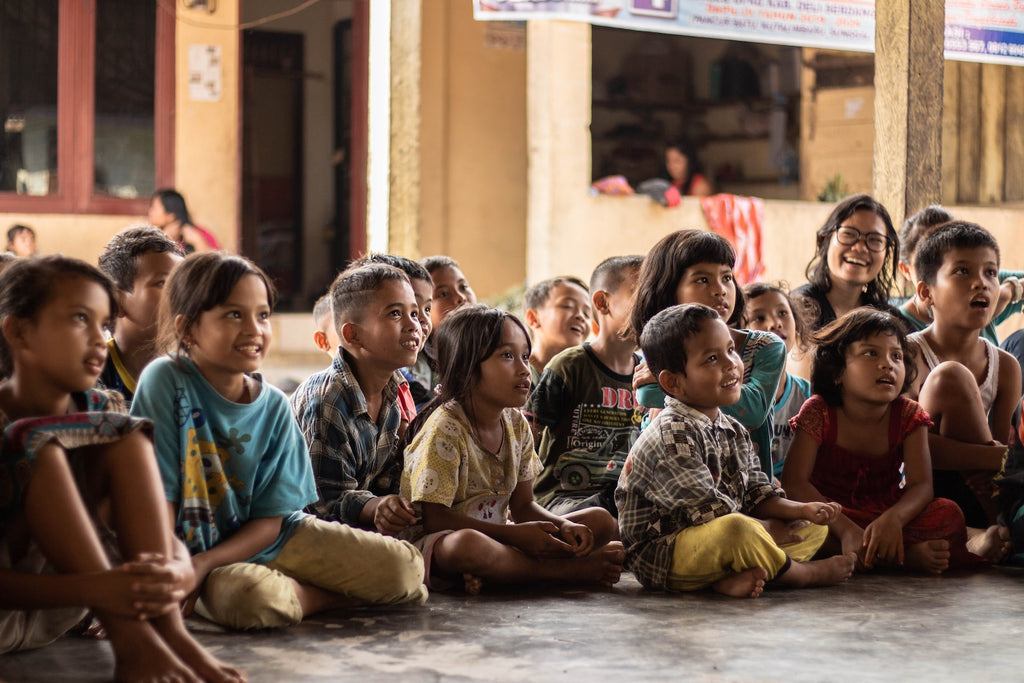 Group of children sitting of the floor, smiling and learning.