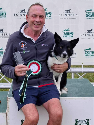 Alan with Ticket the black and white collie under his arm showing their trophy and rosette