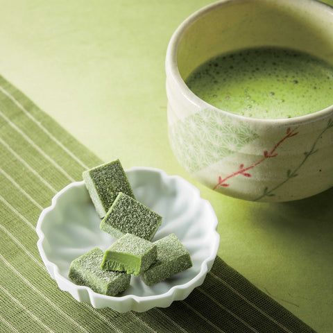 Image shows green chocolate blocks on a plate together with a cup of green tea.