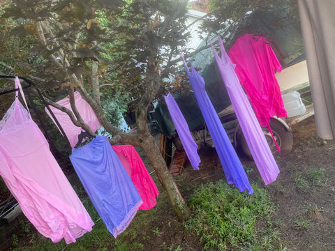 hand dyed clothing hanging on trees in yard after dying process