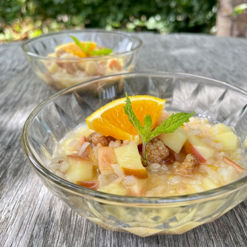 Creamy white rice apple pudding with orange slice and fresh mint topping