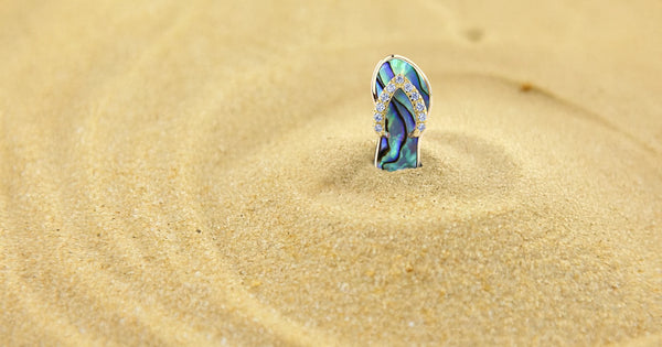 Slipper Pendant with Abalone and Diamonds stuck upwards in beach sand