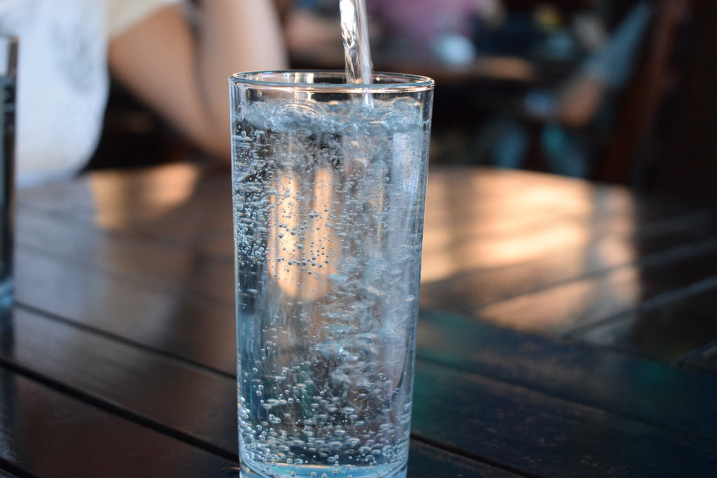 Wasser wird ins Glas eingeschenkt