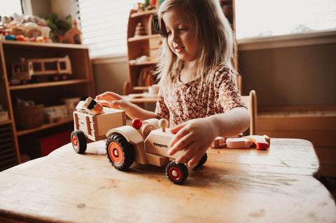 girl playing with fagus farm tractor and trailer