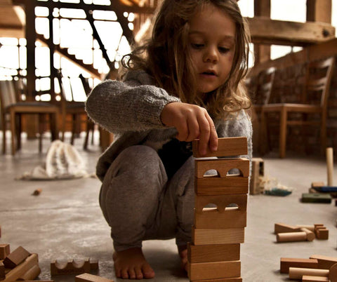 girl playing with wooden story blocks