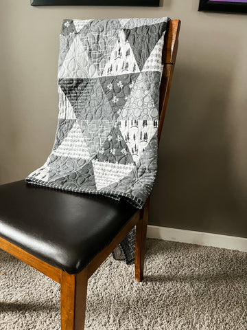 Photograph of a quilt draped on a chair.