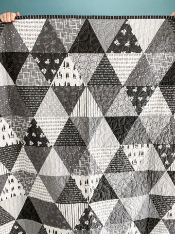 Photograph of hands holding up a quilt.
