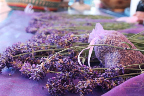 Abgeschnittener Lavendel auf Tisch neben gefüllten Lavendelsäckchen